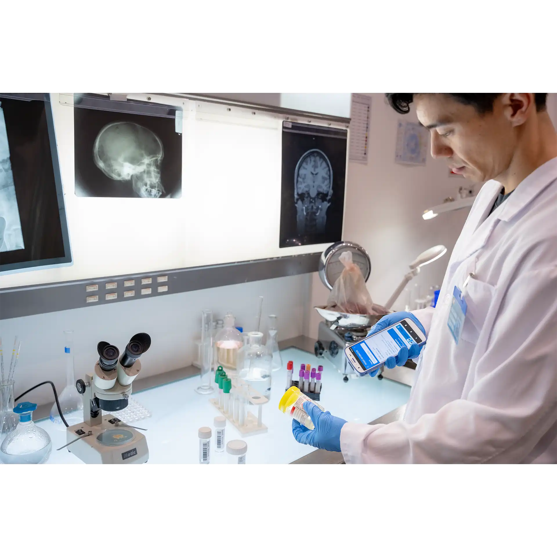 Zebra HC20/HC25/HC50/HC55 MDE Gerät im Labor, Display eingeschaltet, Bedienung mit Handschuh, Laborutensilien sichtbar.