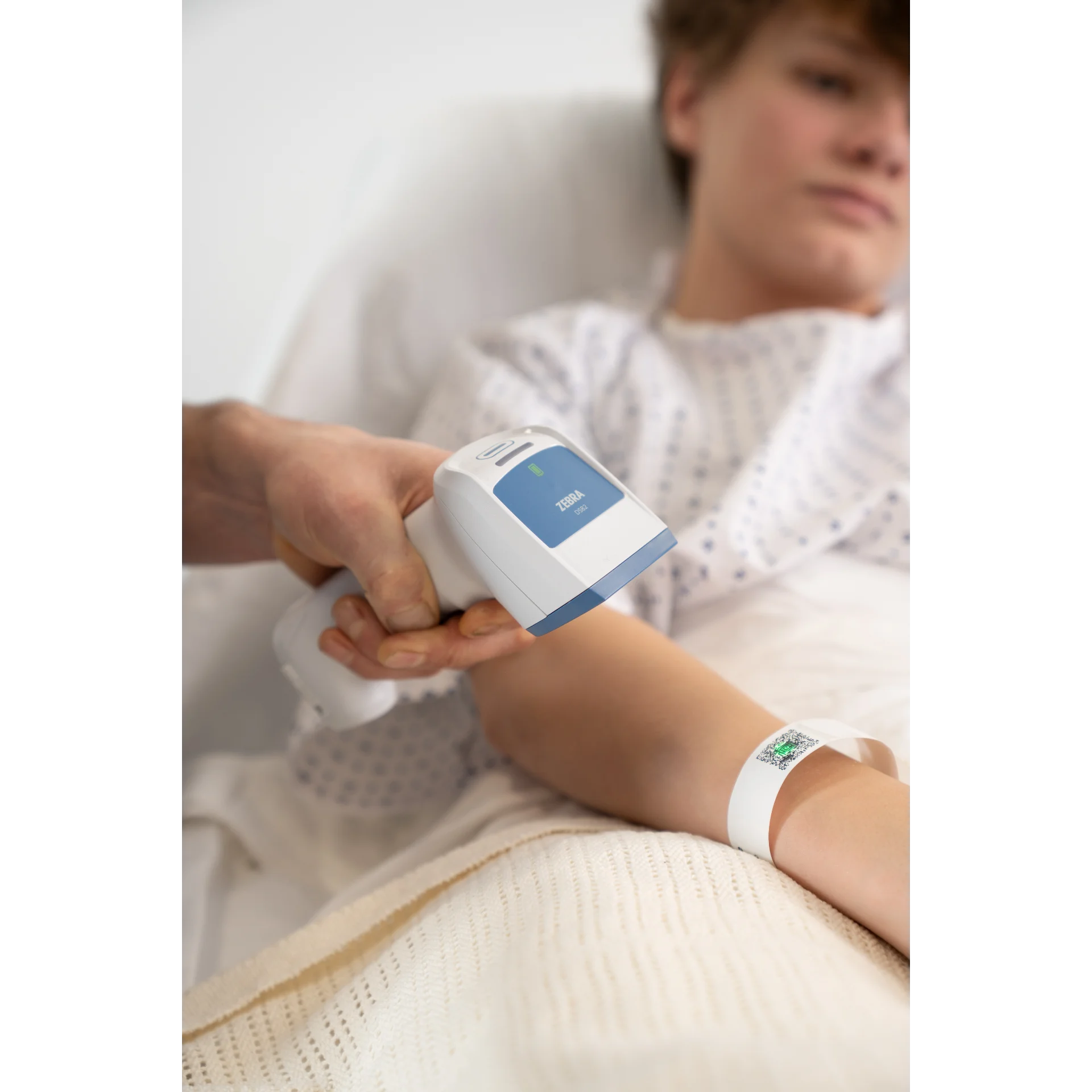 Barcode Scanner Zebra DS8288-HC – Nahaufnahme seitlich beim Scannen eines Patientenarmbands am Handgelenk eines Kindes, LED leuchtet, am Griff