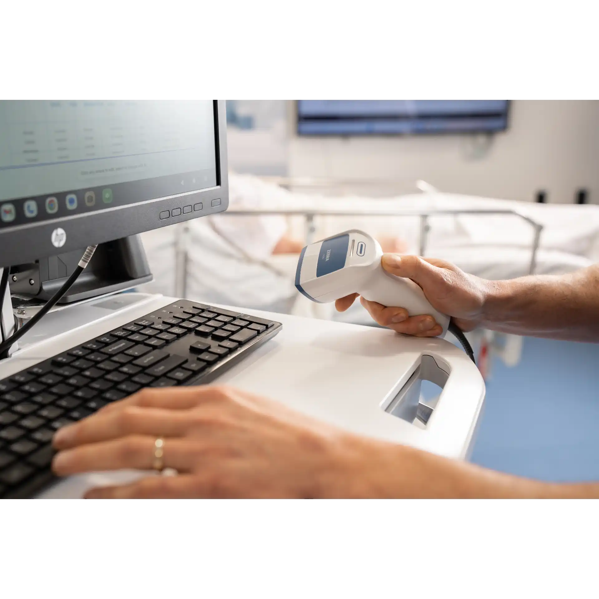 Barcode Scanner Zebra DS8208-HC – seitliche Nutzung an PC-Tastatur und Monitor im Patientenzimmer, oberes Bedienfeld sichtbar, Gerät ohne Display