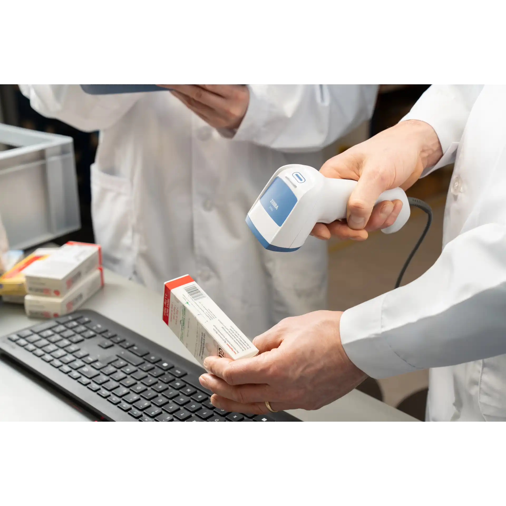Barcode Scanner Zebra DS8208-HC – schräge Ansicht in Hand, Scan einer Medikamentenpackung über Tastatur, Frontfenster zeigt auf Barcode