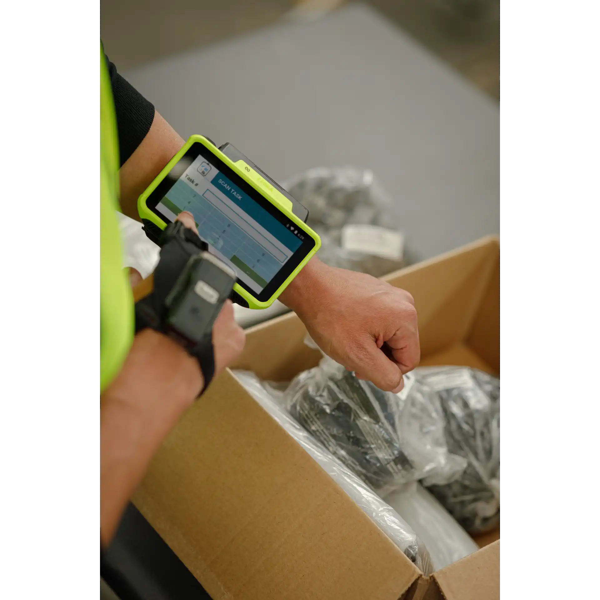 Wearable Zebra WT6400 – seitlich mit eingeschaltetem Display und RS5100 beim Arbeiten im Karton