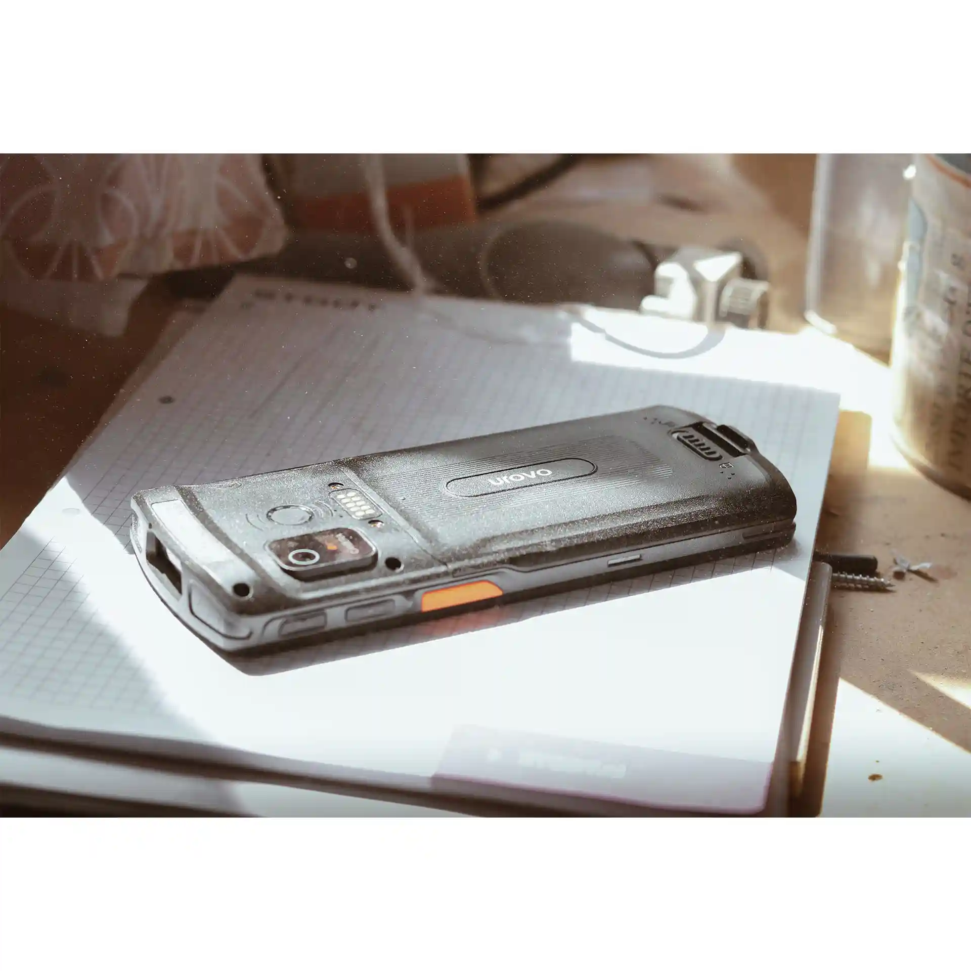 Rückseite eines Urovo DT66 MDE Geräts auf einem Tisch in einer schmutzigen Werkstatt